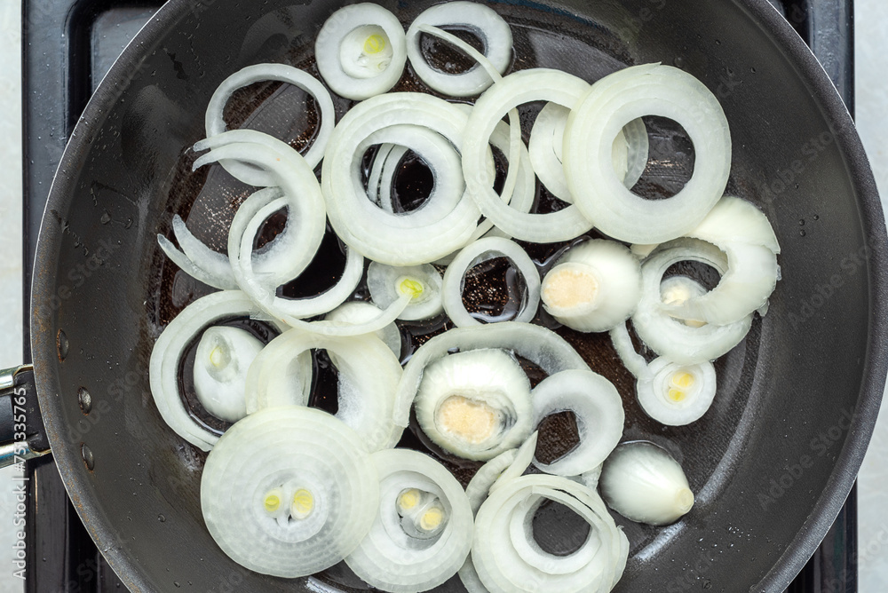 The onion rings are fried in oil in a frying pan. The onion rings are fried in oil in a frying pan.