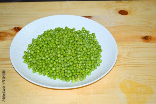 green pea in dish on wooden board. Fresh peeled peas ready for cooking. bowl of green peas. 