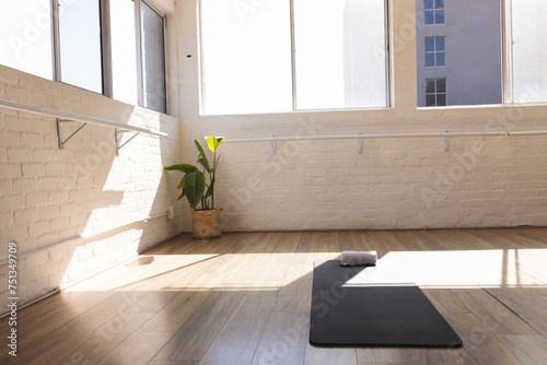 A yoga mat and towel await in a sunlit studio with copy space photo