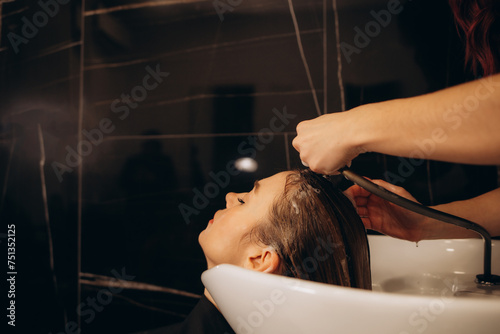 hairdresser washing client's hair at salon. happy young women customer relax and comfortable while washing hair, luxury hair spa by professional hairstylist photo