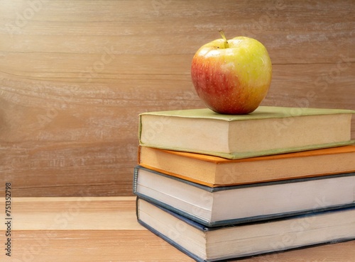 Books stack with apple on it, isolated on wooden desk