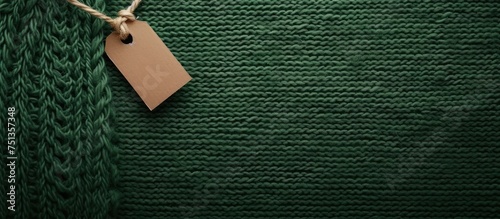 A green knitted sweater is depicted with a white tag hanging from it. The tag likely contains information about the clothing care and composition. The sweater appears to be in new condition.