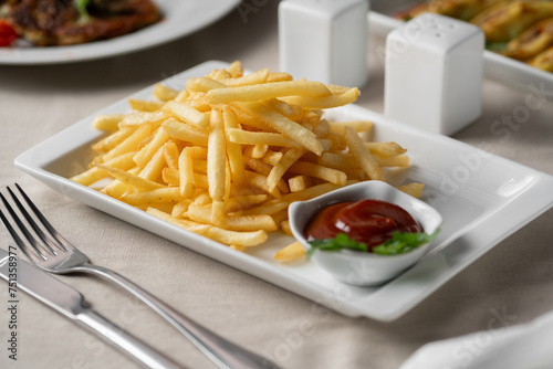 Plate of french fries potatoes served with ketchup on white plate. Unhealthy food