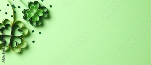 Four leaf clover paper cut with confetti on green background. St. Patricks day concept.