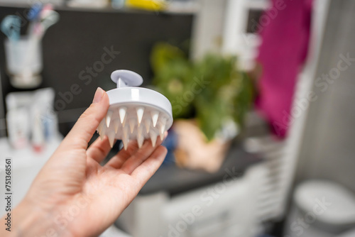Wallpaper Mural Silicone Exfoliator Massager brush for circulation and follicle stimulation for optimal scalp health in woman hand. Silicone Scrubber in the bathroom Torontodigital.ca