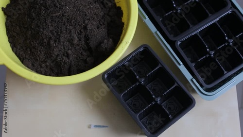 Preparing the soil for seedlings. The owner pours the soil and fertilizer into one container for mixing and use for sowing seeds.