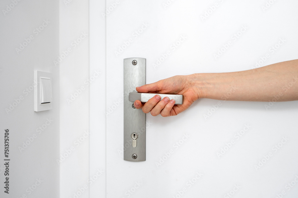 Cropped shot of female hand hold metal handle with keyhole and opening door Cropped shot of female hand hold metal handle with keyhole and opening door