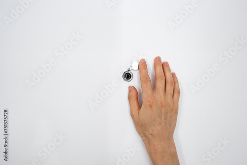 Cropped shot of woman watching through peephole at front door in apartment photo