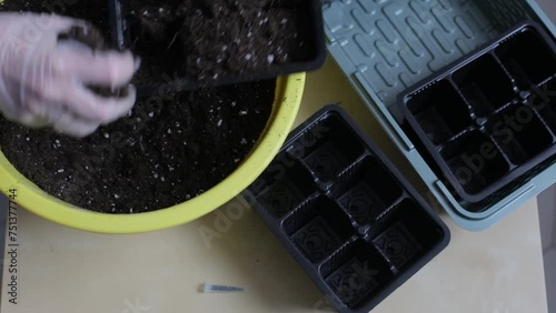 Hands in gloves mix the soil with useful additives and prepare for planting.