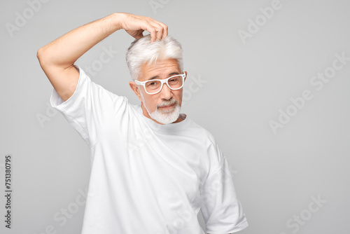 Confident senior man with glasses posing on a gray background.