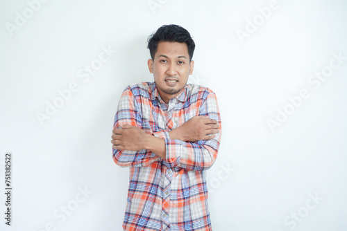 Young man with beard wearing casual flannel shirt shaking and freezing for winter cold with sad and shock expression on face photo