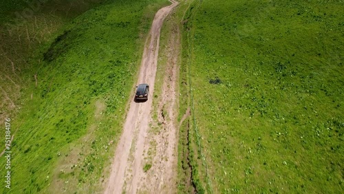 Drone: flies behind a car along the valley of the mountains of Kyrgyzstan
