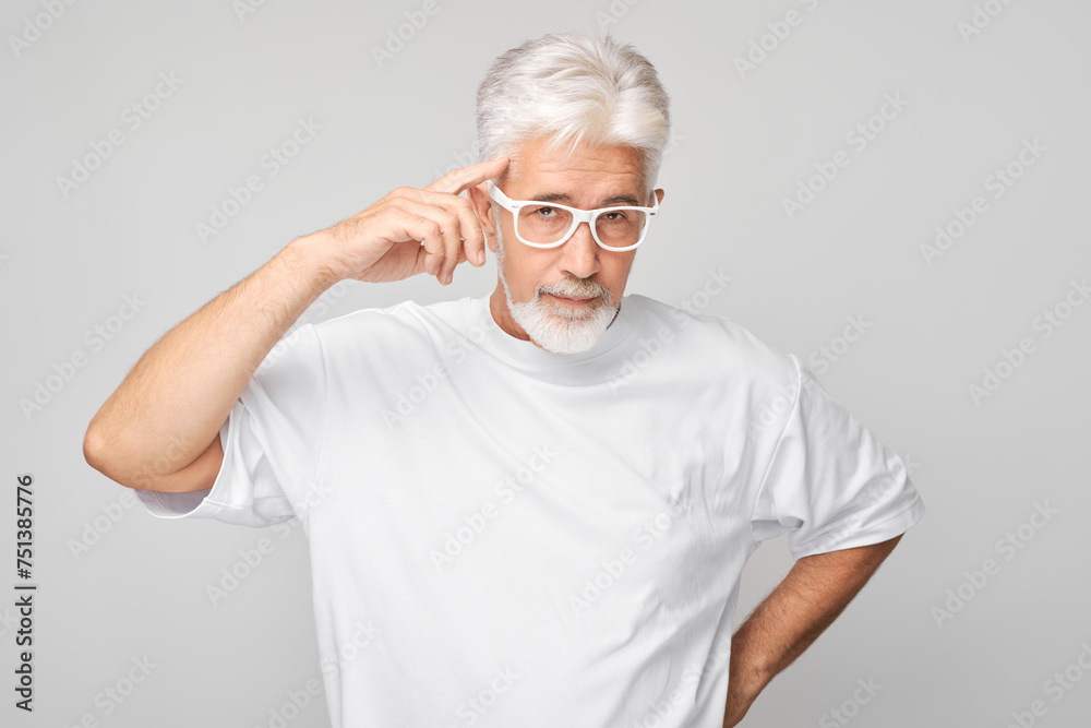 Senior man with glasses making a thinking gesture, isolated on a gray background. Senior man with glasses making a thinking gesture, isolated on a gray background.