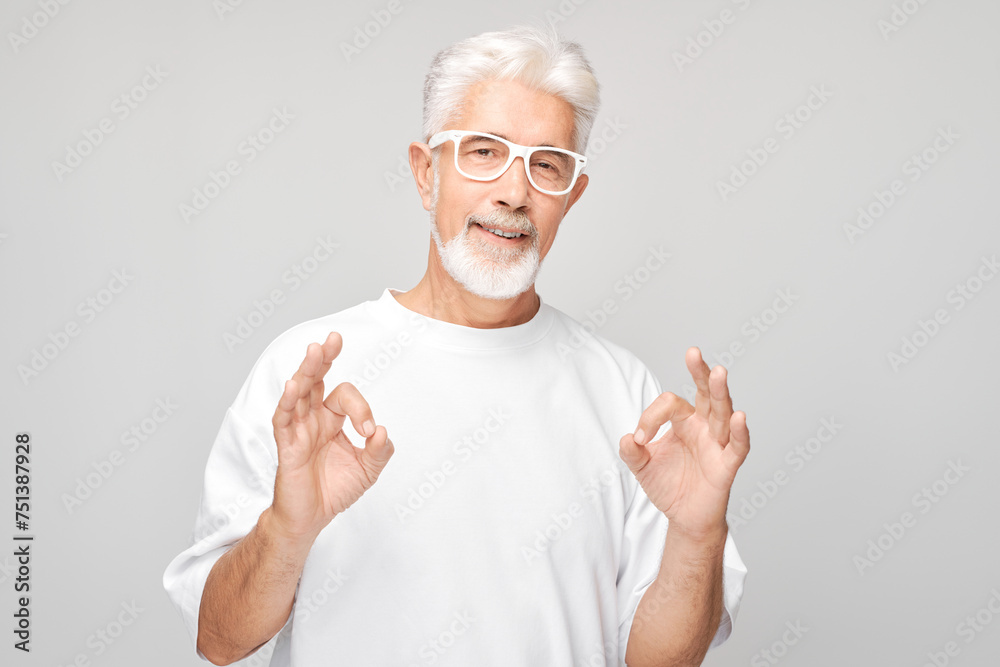 Senior man with glasses making OK gesture on a gray background. Senior man with glasses making OK gesture on a gray background.