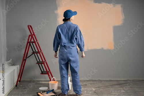 Rear view of woman painter standing near wall getting ready to paint photo