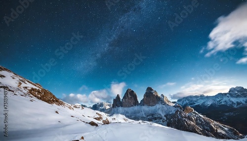 starry sky over snowy mountains at night in winter beautiful landscape with snow covered rocks blue clouds and star mountain valley © Lauren