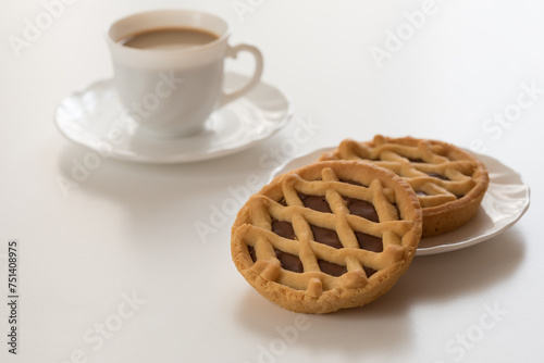 Mini crostate al cioccolato con tazzina bianca di caffè su tavolo bianco