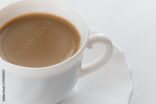 Tazzina bianca con caffè e piattino su tavolo bianco