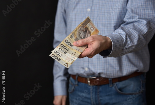 Mezczyzna trzymajacy polskie banknoty, gotowka. Plik banknotow 200 zlotych.