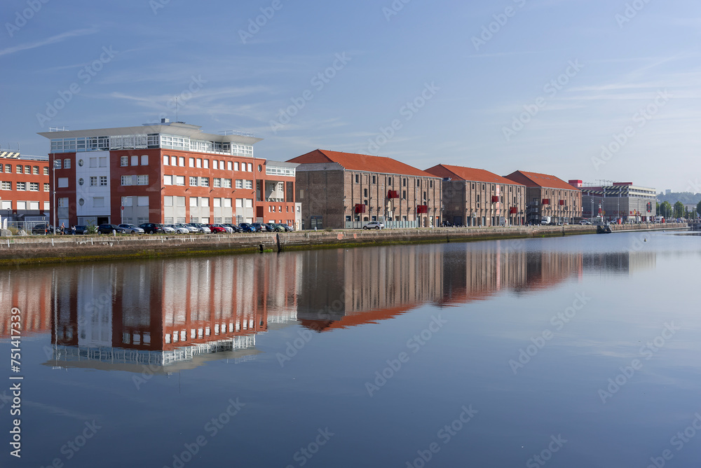 View of a basin with its old brick industrial buildings transformed into shopping center and reflections on the water.