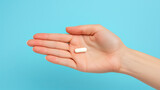 A hand holding two white capsules against a blue background. Ai generative illustration