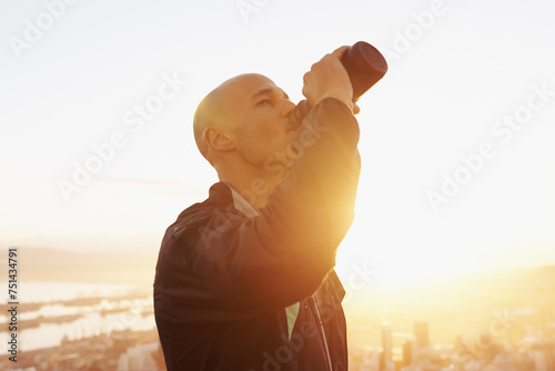 Man, fitness and drinking water with sunset for natural sustainability, break or outdoor hydration. Thirsty male person or athlete with liquid bottle after workout, exercise or training in nature