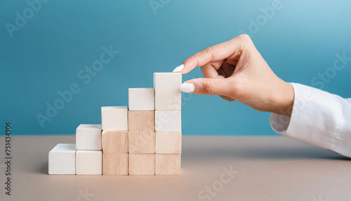 Business concept growth success process, Close up man hand arranging wood block stacking as step stair on paper blue background, copy space.