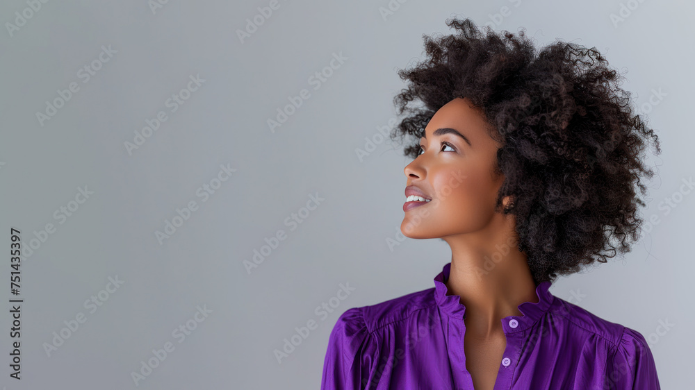 Afro woman wearing purple shirt smile looking up isolated on gray Afro woman wearing purple shirt smile looking up isolated on gray