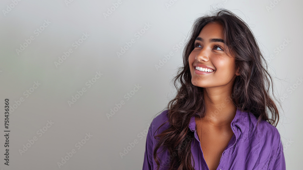 Indian woman wearing purple shirt smile looking up isolated on gray Indian woman wearing purple shirt smile looking up isolated on gray