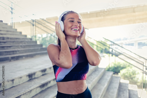 Fototapeta Naklejka Na Ścianę i Meble -  Fitness, healthy and young woman listening to music on a wireless headset while training outdoors on stairs. Female running or sports workout with motivation, wellness and training podcast.