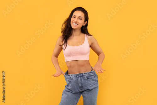 Cheerful Lady Wearing Oversize Jeans Compare Size After Slimming, Studio © Prostock-studio