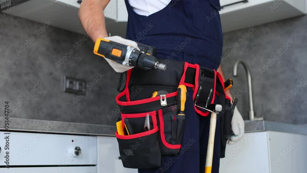 Handyman with a tool belt and craft equipment pulls out a drill. Handyman with a tool belt and craft equipment pulls out a drill.