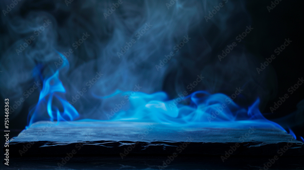 Blue fire with blue flames on a slate plate with dark background and smoke