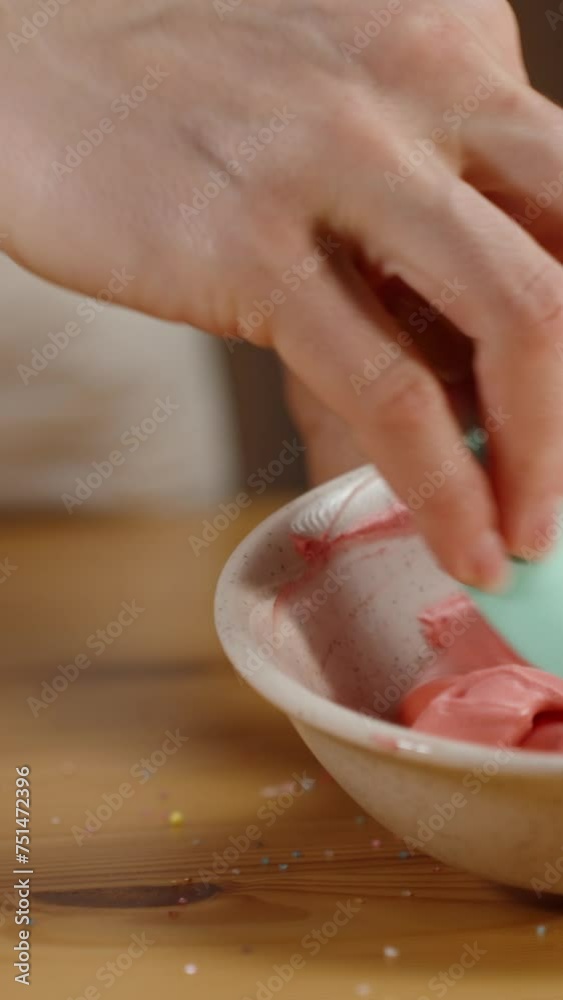Various sprinkles and decorations on the table while the confectioner mixes pink cream for cupcakes. Various sprinkles and decorations on the table while the confectioner mixes pink cream for cupcakes.
