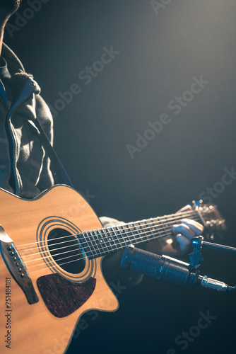 The studio microphone records an acoustic guitar close-up.