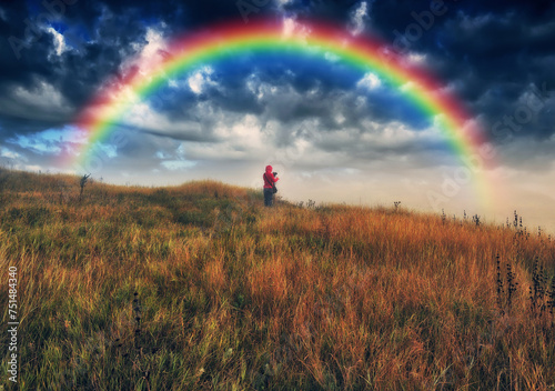 rainbow over the meadow. tourist enjoys the view. scenic landscape © sergnester