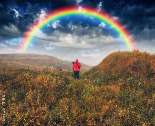 rainbow over the meadow. tourist enjoys the view. scenic landscape © sergnester