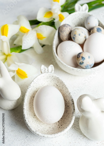 Easter natural colors eggs in bowls with bunny ears  bunnies  white Iris flowers on white close up.