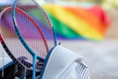 Badminton sport equipments, rackets and sportbag placed on floor with blurred rainbow flag background, concept for popular sports with all gender and lgbt people around the world. photo