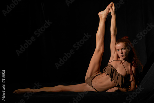 Red hair cauasian girl acting in yoga black isolated photo