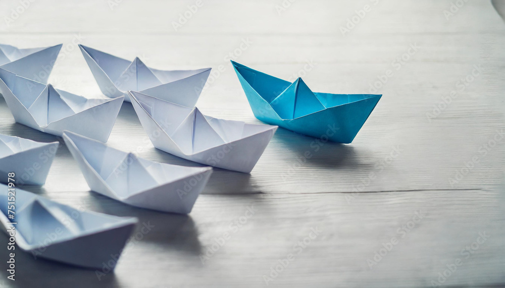 blue paper ship leads a fleet of white paper ships on a modern white table, symbolizing leadership and teamwork blue paper ship leads a fleet of white paper ships on a modern white table, symbolizing leadership and teamwork
