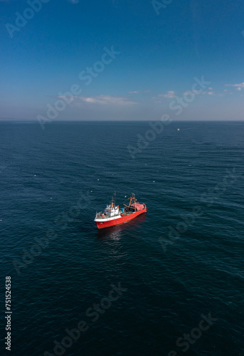Aerial view to a red fishing vessel in sea