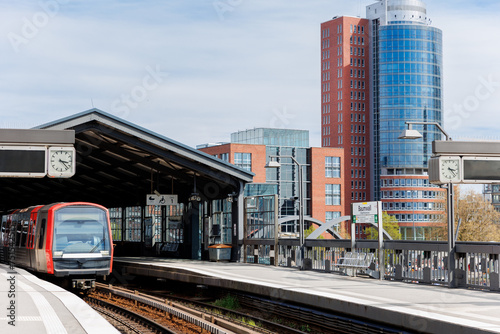 Hamburg Red Unmanned U-bahn Subway train rail Baumwall station on Elevated Track with Hamburger Port Harbor Elbphilharmonie building background blue sky. Hanseatic city commute transport scenic view