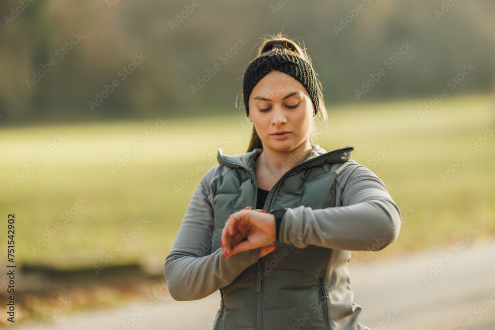 Woman Checking Her Fitness Tracker During a Morning Jog in the Park Woman Checking Her Fitness Tracker During a Morning Jog in the Park