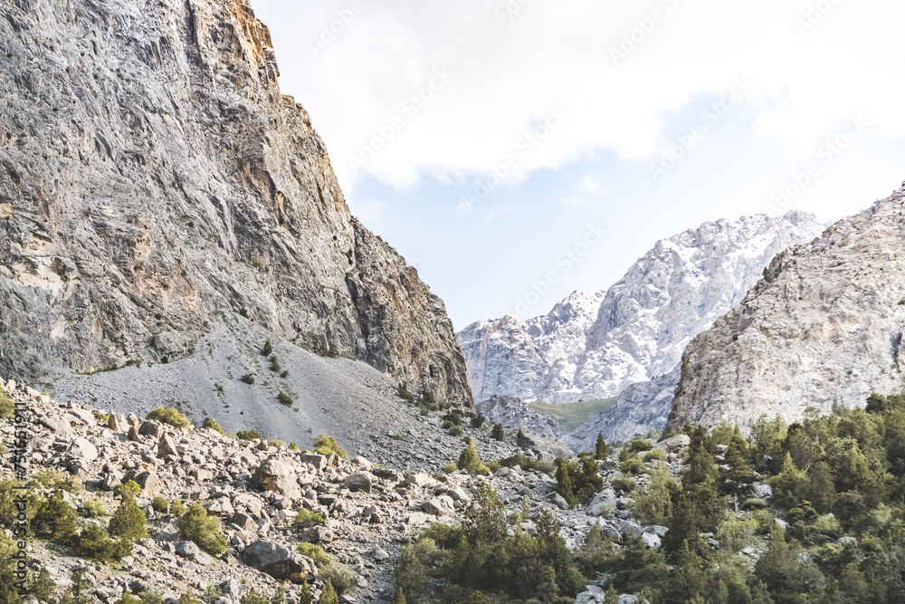 View of the mountain ranges and peaks of the Fan Mountains with glaciers, rocks and vegetation in Tajikistan, mountain panorama on a summer sunny day