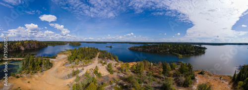 Aerial view of an abandoned polluted mine site next to a beautiful northern lake. The ground is covered in rusty acid generating waste rock. 