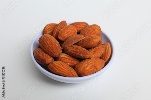Roasted almond in small white bowl, isolated on white background, side view