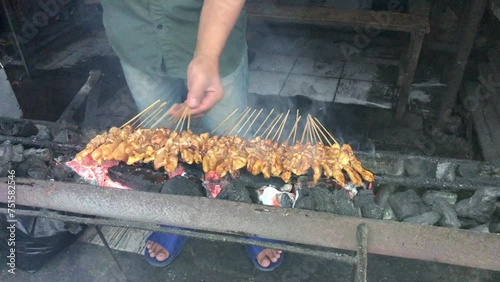 Asian man hand or (penjual sate) is grilling chicken satay. Indonesian street food. photo