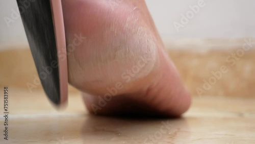 Woman using foot file for removing dead skin from feet at home, woman scrubbing foot process by pumice