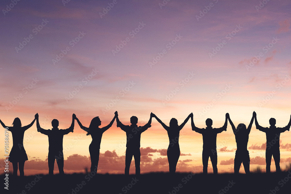 Fototapeta premium Silhouette of people holding hands against sunset background, concept of peace and victory